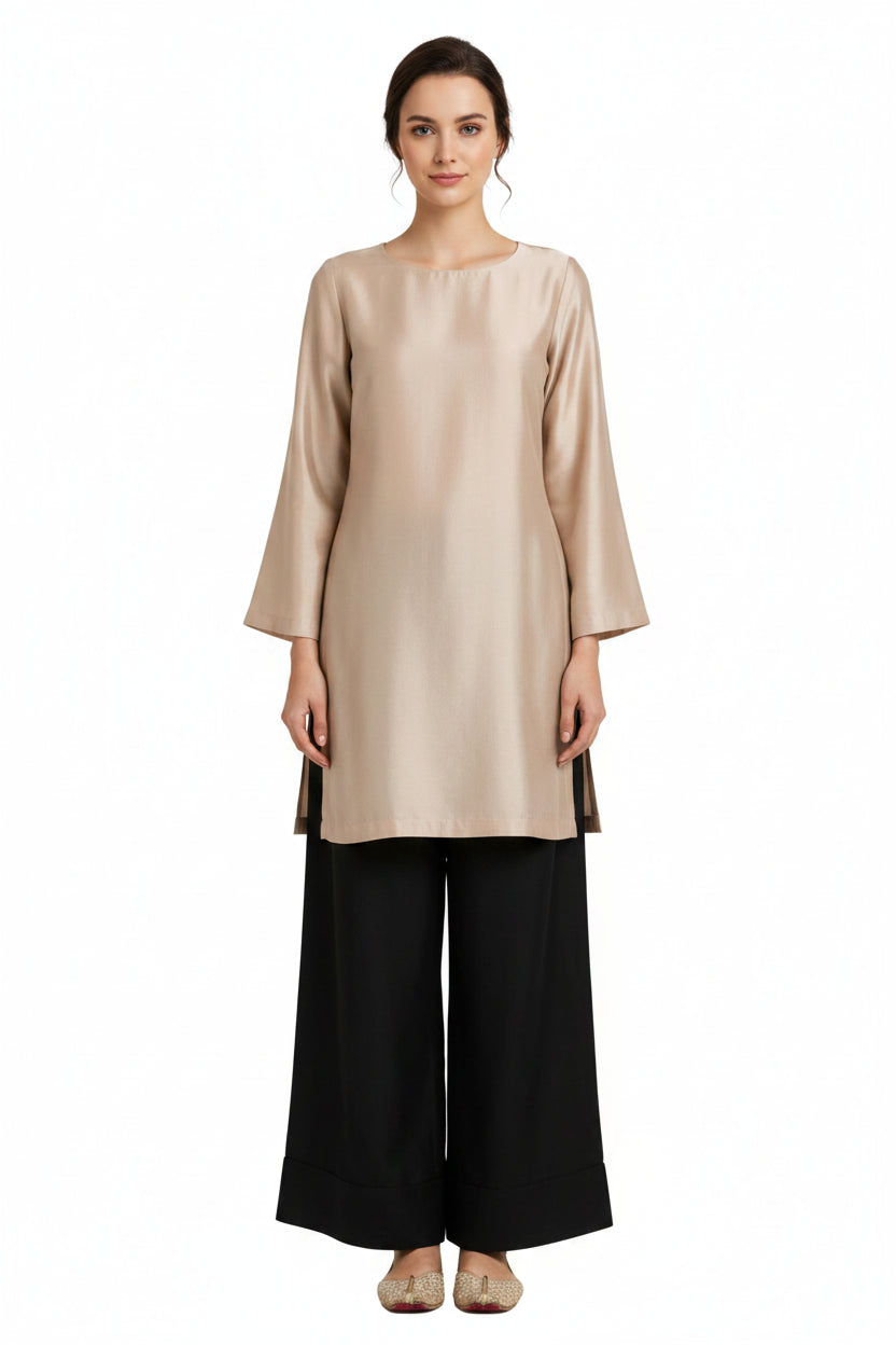 A woman shown from the back wearing a light beige long-sleeve tunic top and black wide-leg pants, standing against a plain white background.