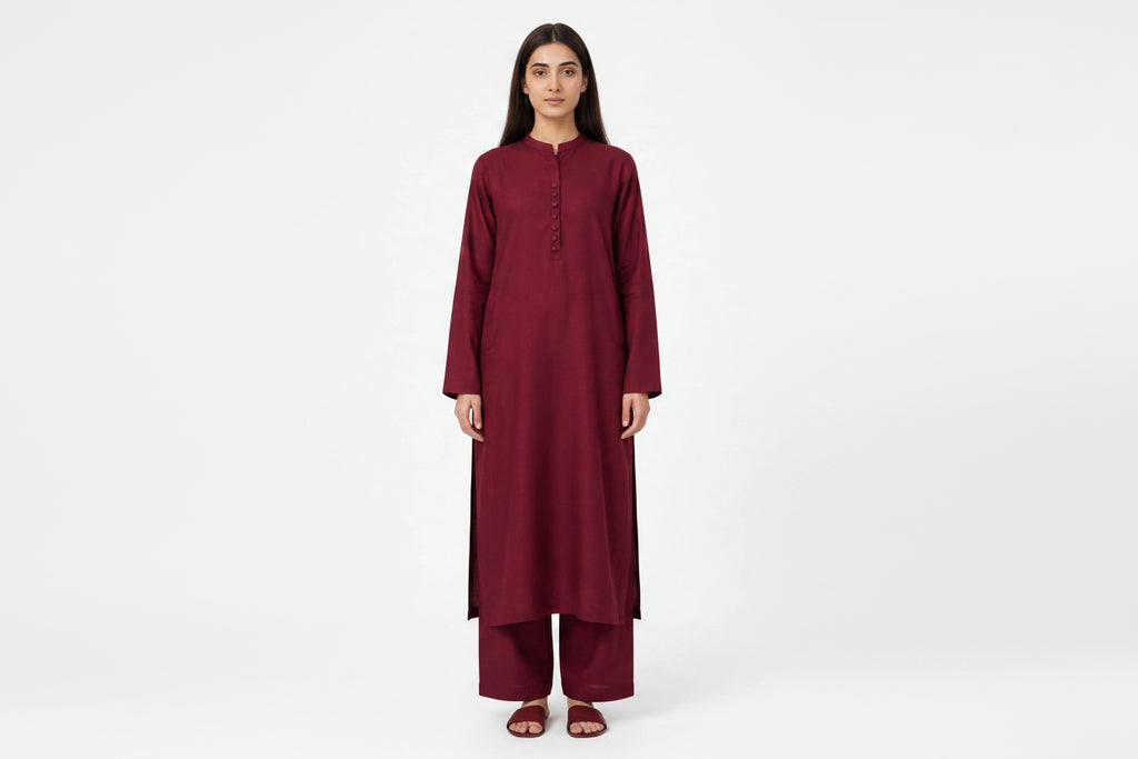 A woman modeling a long-sleeved maroon kurta and matching palazzo pants set against a plain white studio background.