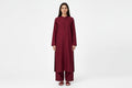 A woman modeling a long-sleeved maroon kurta and matching palazzo pants set against a plain white studio background.