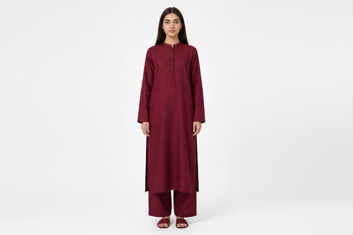 A woman modeling a long-sleeved maroon kurta and matching palazzo pants set against a plain white studio background.