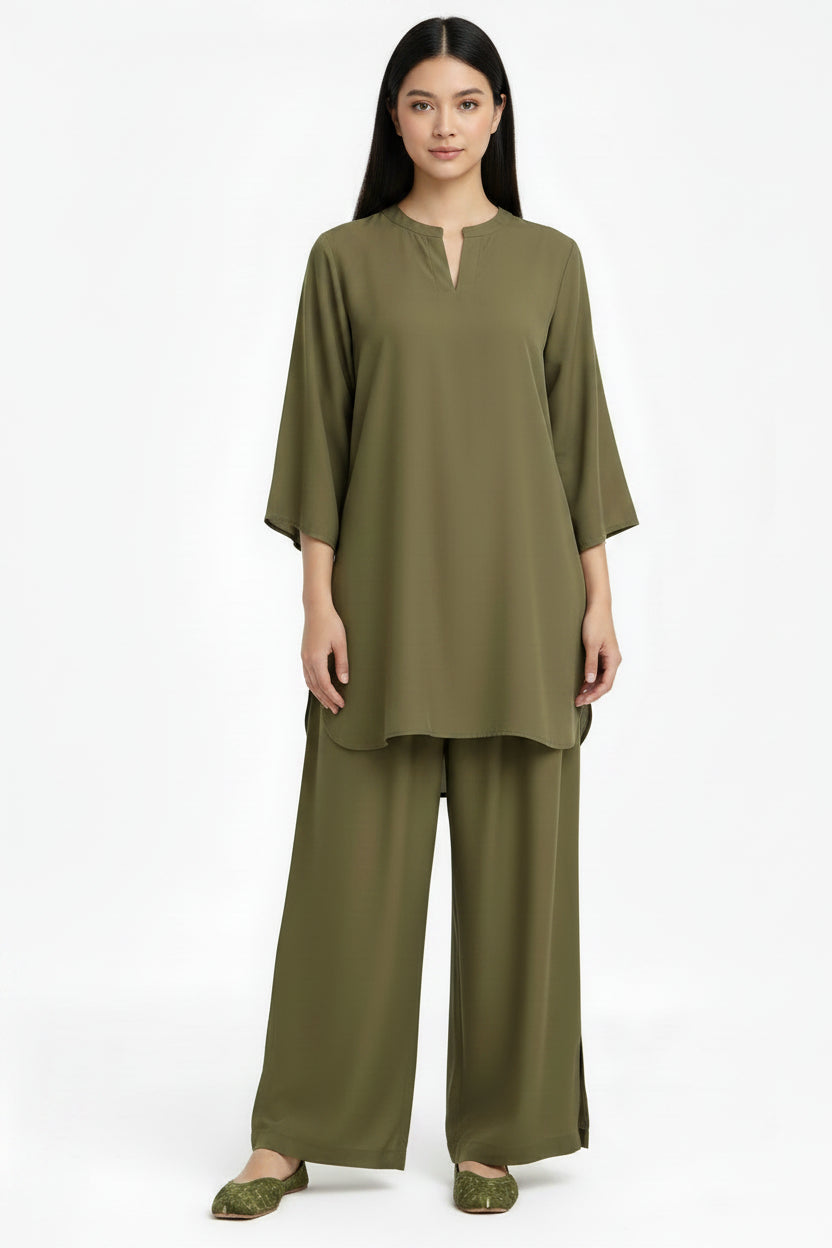 A woman modeling a matching olive green two-piece lounge set consisting of a short-sleeve tunic top with a split neckline and wide-leg pants, photographed against a plain white studio background.