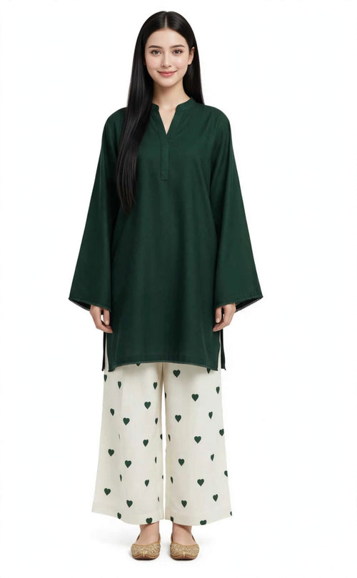 A woman modeling a dark green long-sleeve tunic with a split neckline, paired with off-white wide-leg pants featuring a green heart pattern, against a plain white background.