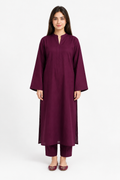 A woman modeling a deep plum-colored kurta with matching pants against a plain white studio background.